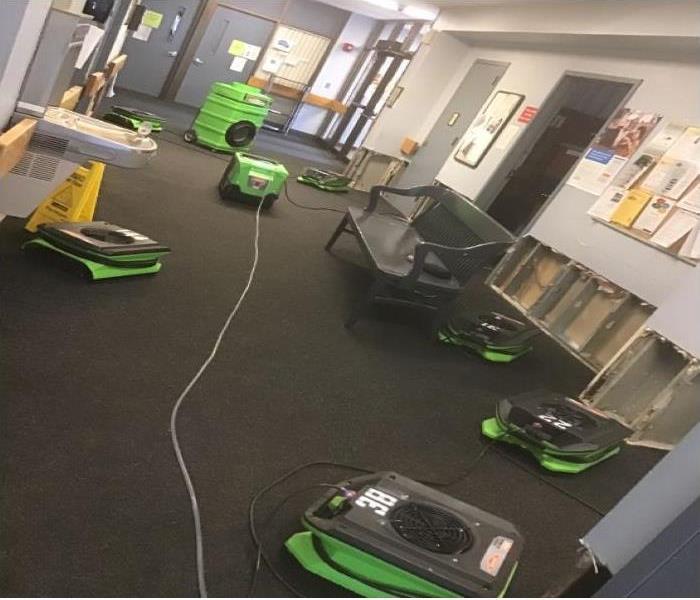 drying equipment in hall way of building with flood cut walls