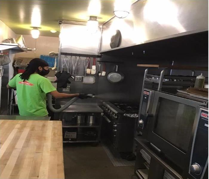 technician sanitizing commercial grade oven