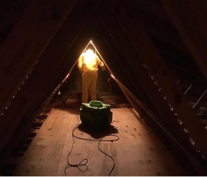 air scrubber is attic with technician in protective gear in background