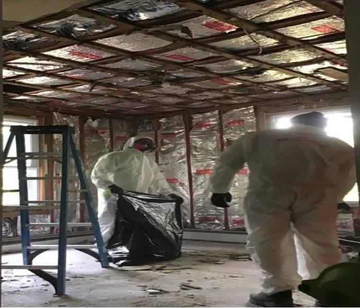 technicians in PPE removing debris from demolition