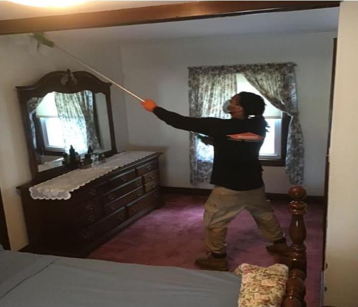 technician cleaning soot off a ceiling 