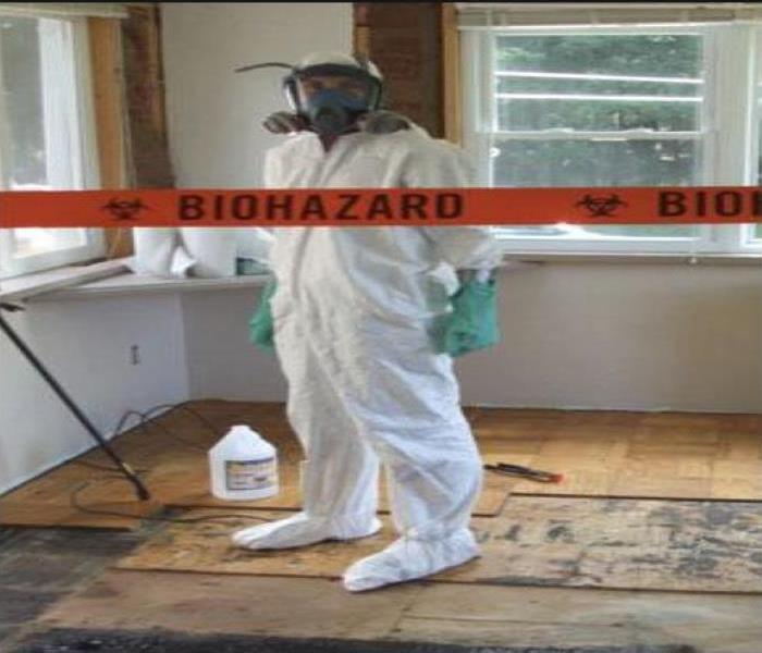 red bio hazard tape against a background with technician in a tyvek suit 