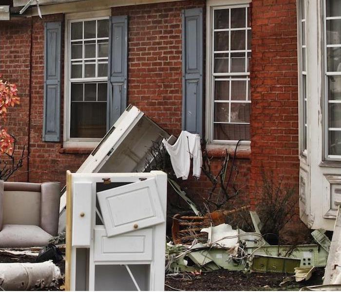 damaged furniture and other home items sitting outside of red brick house