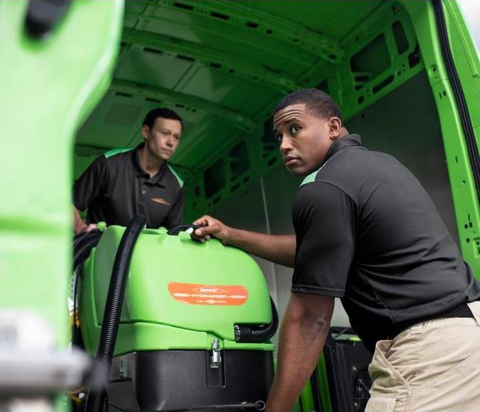 Technicians removing water damage equipment from a van